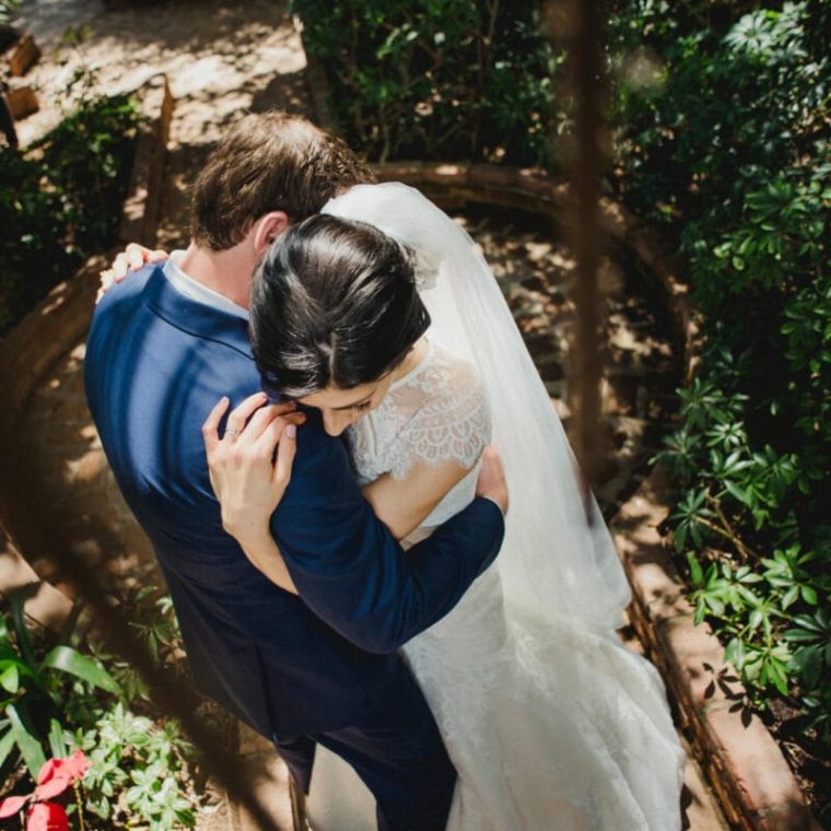Novios abrazados en un camino rodeado de naturaleza, fotografía íntima de boda.