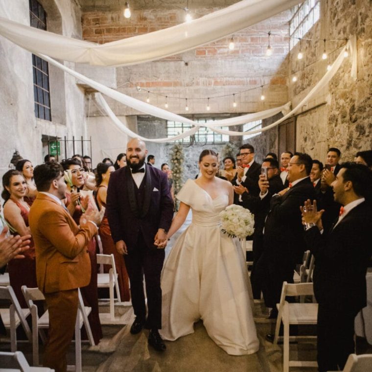 Recién casados caminando juntos por el pasillo en una ceremonia de boda en interior.